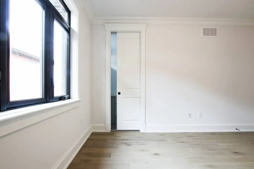 Elegant white pocket door partially open, showcasing seamless integration into a contemporary bedroom wall.