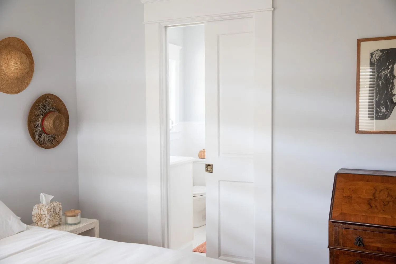 Wooden pocket door with intricate patterns, dividing a cozy home office and a bright living area.